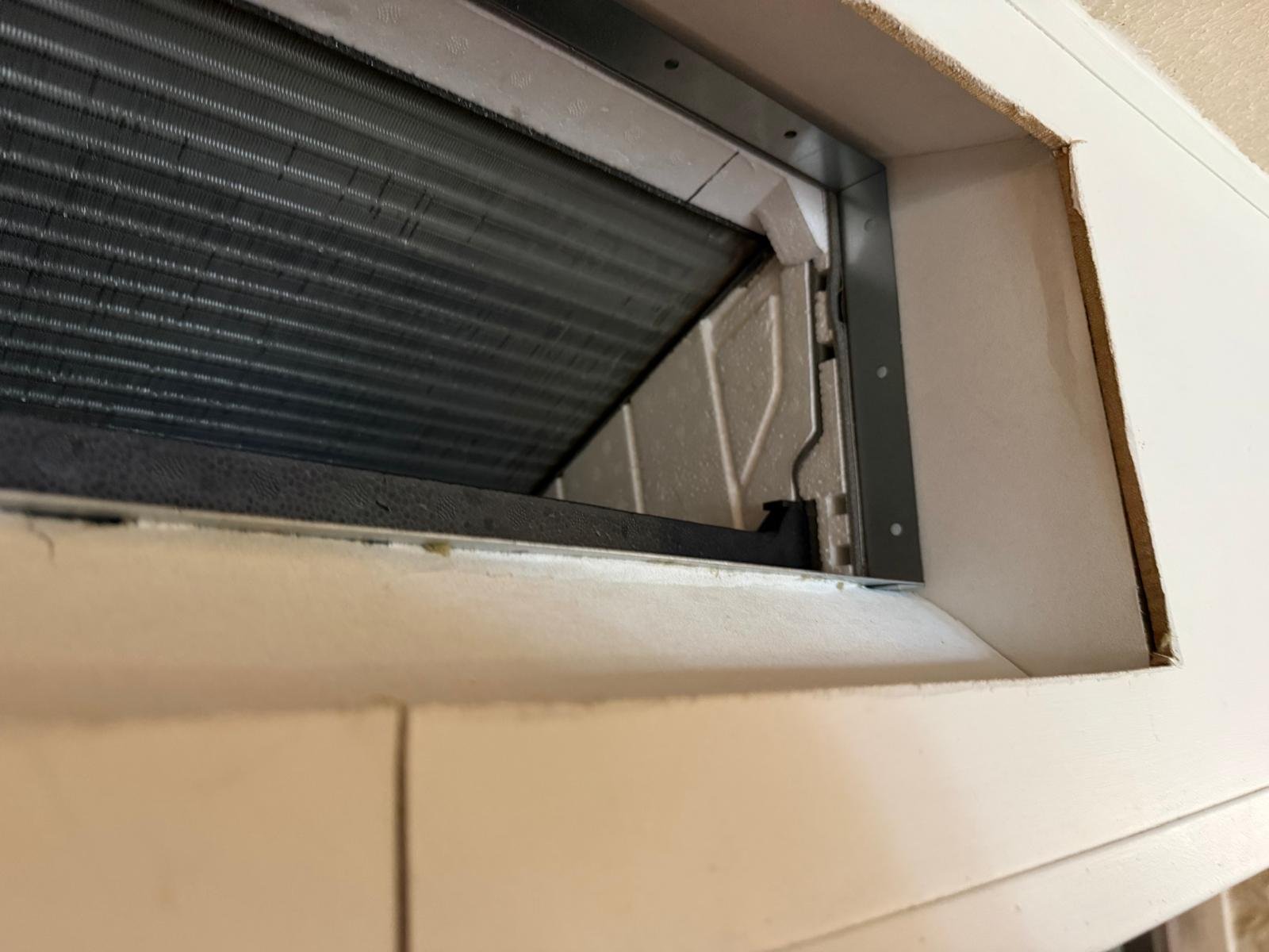 Batterie d'échange d'une climatisation gainable vue depuis la grille de reprise du faux plafond