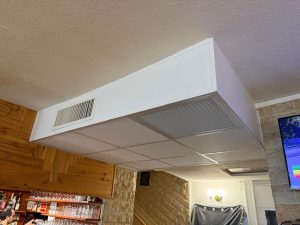 Caisson blanc au plafond d'une pizzeria avec grilles de soufflage et de reprise de la climatisation gainable